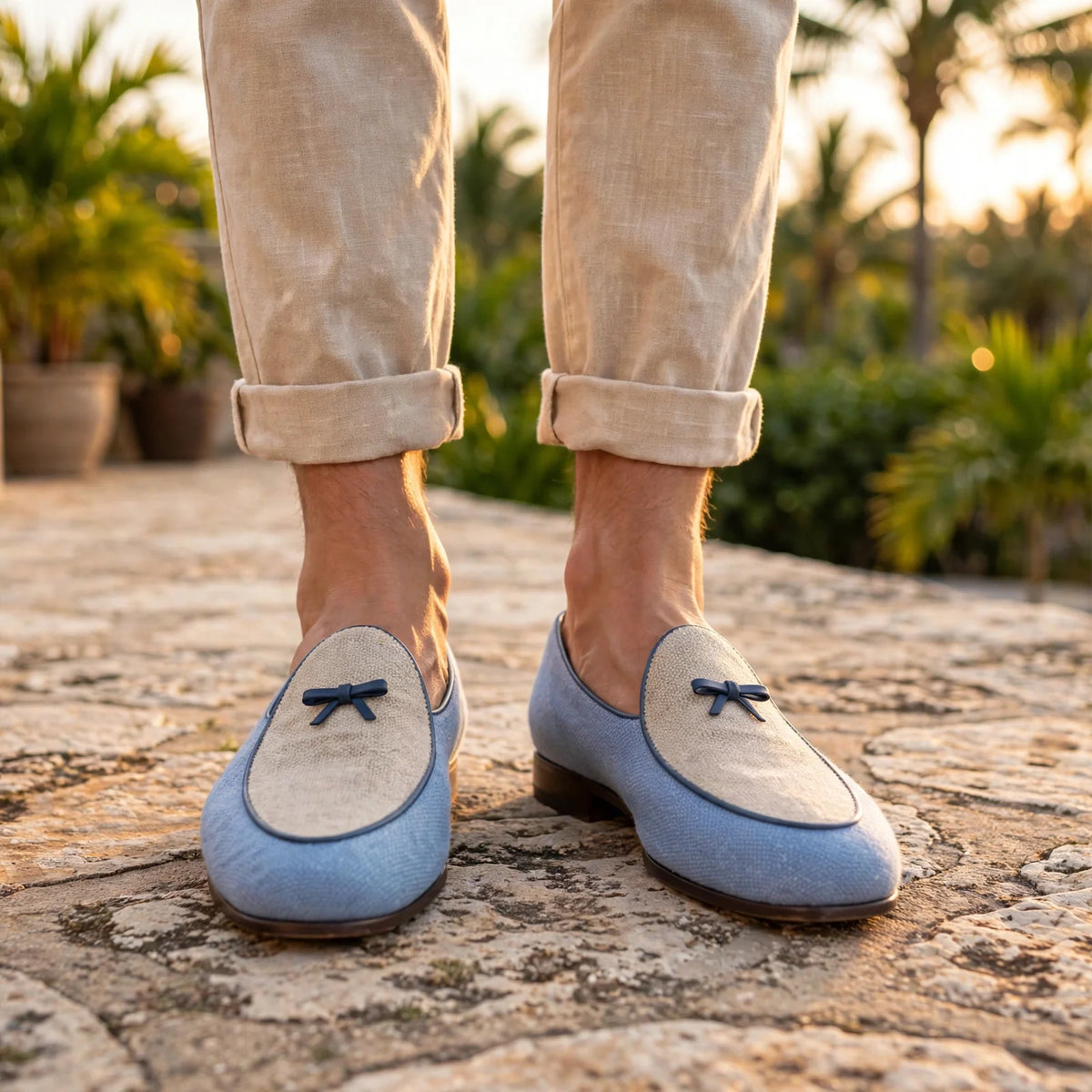 Blue and ice linen Belgian slipper with navy trim and bow, worn with rolled linen trousers on a resort terrace at golden hour